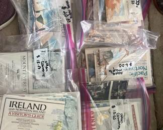A collection of vintage postcards, travel guides, and printed ephemera including an Ireland postcard and various other paper items stored in clear plastic sleeves.