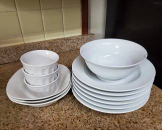 Collection of white ceramic dishes including dinner plates, bowls, and smaller plates. Appears to be a basic everyday dinnerware set in good condition.