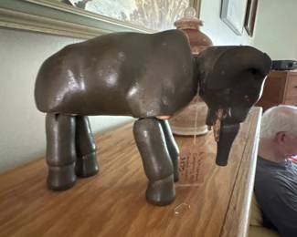 Decorative leather elephant with articulated legs, likely mid-20th century. The piece features a dark brown leather body with metal or wooden jointed legs.