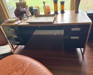 Dark wood desk with tapered legs and multiple drawers, featuring a clean mid-century modern design. The desk has a spacious work surface and appears to be in good condition.