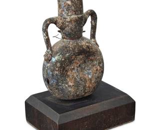 103 A Roman glass amphoriskos 1586-330 BCE Mounted on a display armature with black painted wood base Height without ring 3 3/4 in., width 2 in., depth 7/8 in.; height on stand 4 3/4 in. Estimate: $300 - $500