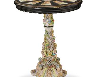 167 A Carl Thieme porcelain occasional table Late 19th century The ebonized wood tabletop with gilt painted accents, set with ten painted porcelain panels, each depicting courting figures, centering a middle panel with putti, raised on a painted porcelain pedestal profusely decorated with figures, masks, and floral elements in relief, ending in four scroll legs, with a middle porcelain support element conformingly decorated Marked to underside: blue painted T over crossed lines; incised: 794 4 pieces Height of tabletop 3 3/4 in., diameter 25 3/4 in.; height of base 23 3/4 in., width 15 1/4 in., depth 15 3/4 in.; height of middle piece 6 3/4 in., diameter 5 3/4 in. Estimate: $3,000 - $5,000