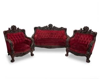 290 An American Art Nouveau carved wood three piece salon suite Circa 1900, attributed to S. Karpen & Bros. Comprising a loveseat and a pair of armchairs, each with tufted velvet upholstery and ornately carved with floral and foliate motifs, crested by a maiden 3 pieces Height of loveseat 42 in., width 60 in., depth 32 in.; height of armchairs 42 1/2 in., width 34 1/4 in., depth 32 in. approximately Estimate: $1,000 - $2,000
