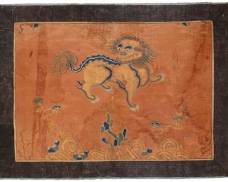 54 A Chinese embroidered silk panel of a 'foo dog' Late Ming/early Qing dynasty (17th-18th century) A silk panel fragment featuring a central foo dog or Chinese guardian lion in a stylized landscape with clouds or smoke and flame motifs, worked in silk and gilt thread embroidery. and with an added textured woven border; the panel professionally mounted to a fabric backing and framed under acrylic Sight 17 x 23 in. approximately Estimate: $1,000 - $2,000