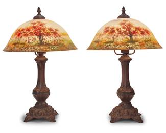 244 A pair of American reverse painted lamps 20th century Each with brown painted metal base issuing a single light, surmounted by a glass shade painted on the reverse with an autumnal arboreal landscape, electrified Each unmarked 2 pieces Height of each overall 20 1/4 in., diameter 13 7/8 in. Estimate: $800 - $1,200