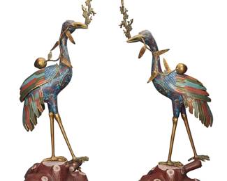 44 A pair of Chinese cloisonné crane candlesticks Late 20th century Each bird with hollow body and removeable wings, raising a tree branch-form standard with a conformingly enameled bobèche, also issuing from the beak a single peach on a branch with leaves 2 pieces Heights 33 1/3-35 in., width of each 14 in., depth 12 1/4 in. approximately Estimate: $900 - $1,200