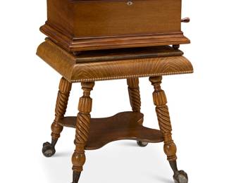268 A New Century Shifter music box 1902-1905 With dual combs, playing 18 1/2 in. diameter type 6 discs (2 included with the lot), housed in a mahogany case and raised on an associated oak stand with metal and glass ball-and-claw feet Serial number: 478 Height of box 13 1/2 in., width 29 in., depth 23 1/2 in.; height of stand 29 1/2 in., width 28 in., depth 28 in. Estimate: $4,000 - $6,000
