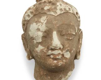 365 A Gandharan stucco head of a Buddha Circa 3rd-4th century BCE (Gupta period) The head displaying a serene, idealized expression with downcast eyes, softly modeled facial features, and full lips, the hair arranged in a smooth cap or topknot, with a simplified treatment characteristic of early classical Indian sculpture Height 6 5/8 in., width 4 1/2 in., depth 4 1/4 in. Estimate: $800 - $1,200