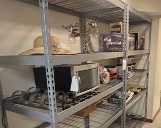 The shelving here contains wine themed items including an Emerson wine fridge, wine bottle holders, popped corks and bottle openers.  The other shelf has painting supplies and covers for deck furniture and wood stacks.