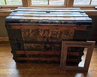 antique dome-top steamer trunk (humpback trunk) from the late 19th to early 20th century, featuring wood and metal construction with patterned tin embossing and wooden slats.