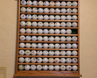 wall-mounted golf ball display rack with approximately 98 collectible logo golf balls