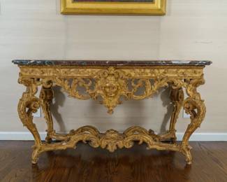 LOT 04 – A French, Late 17th - early 18th c., Louis XIV Regence Console Table. A carved giltwood console of unusual transitional design, the pierced apron centred by a mask amid acanthus scrolls, beneath a Rouge Royale marble top. Acquired from Pelham Galleries, London.