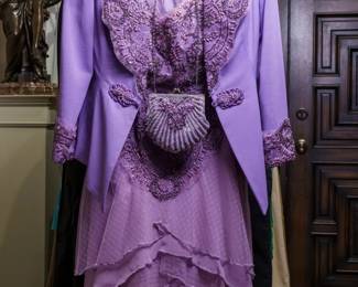 LOT 65 – Exquisite Lavender Lace, Silk & Pearl Beaded Evening Ensemble, with Matching Handmade Handbag. A breathtaking lavender lace and silk satin ensemble, lavishly encrusted with gorgeous hand-sewn floral beadwork and pearl beads in fleur-de-lis designs. The beautifully detailed bustle-style top features elegant elbow-length sleeves, richly embellished with matching hand-sewn beading. The bustle top is worn over a tiered lavender silk chiffon skirt, combining flowing silk chiffon with patterned lace to create the appearance of a graceful full-length gown. Designed by famous fashion and costume designer Margi Kent. Sold as a full ensemble set. • Approx. Size ~8 to 8/10; Approx. Measurements: Waist: 30”, Bust: 36, Hips: 36. • Owner’s note: the gowns can be adjusted in size; there is plenty of fabric in the seams.