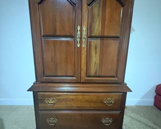 Traditional cherry finish armoire with raised panel doors and brass drawer pulls