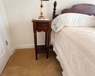 Twin bed with carved wood headboard, nightstand, and table lamp