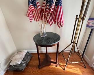 Round marble top accent table, small American flags, and brass display easel