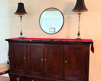 Cherry sideboard buffet with pair of bronze table lamps and round mirror