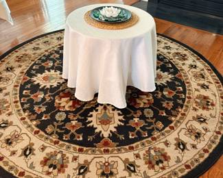 Round Persian style area rug in black and cream with skirted accent table
