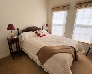 Guest bedroom with twin bed, wood nightstand, and red shade table lamp