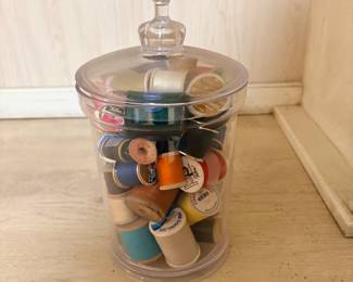 Glass apothecary jar filled with vintage wooden thread spools