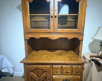 Oak china hutch with glass doors, lighted top, and carved lower cabinet