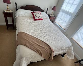 Guest bedroom with wood bed, white quilted coverlet, and nightstands