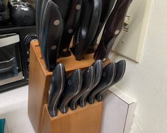 Oster knife set with black handles housed in a two-tier wooden block, showing some signs of use.