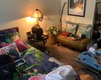 Bedroom furniture and decor, including a floral-patterned bedspread, a wrought-iron side table with a lamp, a small upholstered bench, and a framed Ansel Adams poster.