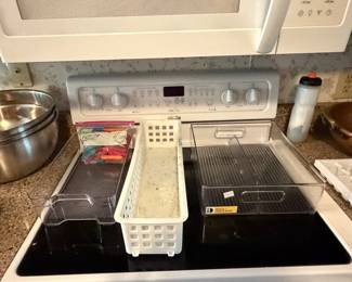 Stainless mixing bowls and plastic storage bins on range top