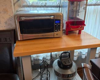 Stainless toaster oven and red popcorn maker on kitchen cart