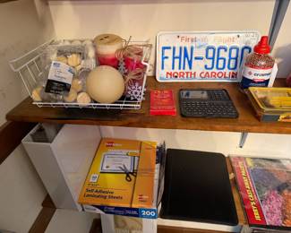 Shelf with North Carolina license plate, calculator, candles and laminating sheets