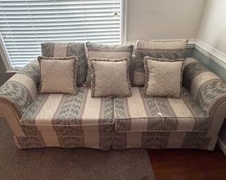 Striped upholstered loveseat with accent pillows