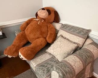 Upholstered sofa with throw pillows and large teddy bear