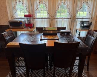 Dark wood dining table with six upholstered chairs and beverage dispenser