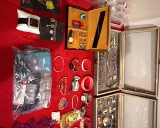 Red lined display case with costume jewelry, wristwatches and earrings