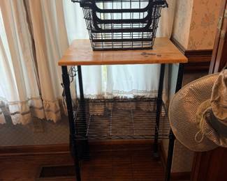 Black metal rolling cart with wood top and hanging wire baskets