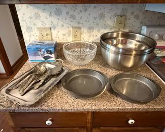 Stainless mixing bowls, cake pans and flatware on kitchen counter