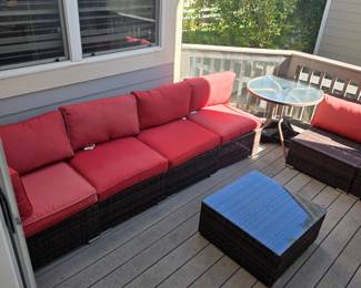 Modern resin wicker outdoor patio sectional set featuring dark brown woven bases, bright red cushions, and a matching square coffee table with a glass top.