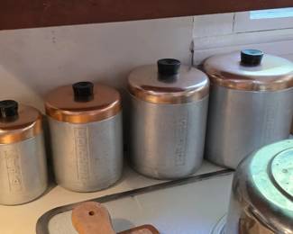 Mid century brushed aluminum kitchen canister set with a copper-toned lid and a black knob