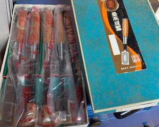 Set of Japanese woodworking chisels in original box, featuring wooden handles and protective plastic sleeves.