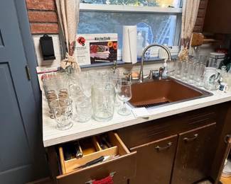 Kitchen counter area featuring an assortment of glassware, stemware, and pitcherson display next to the sink.
