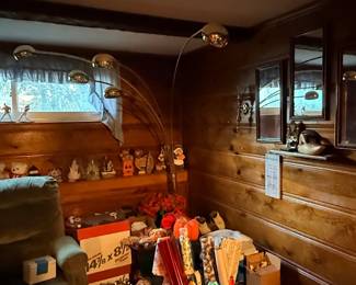 Vintage mid-century modern multi-arm arc floor lamp with brass globes, set in a wood-paneled basement room alongside framed mirrors, a recliner, and assorted decor.