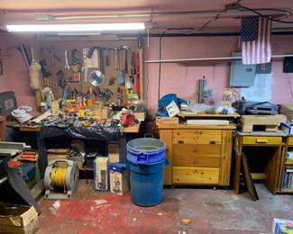 Workshop basement setup featuring a fully stocked pegboard with hand tools, wooden workbench, power tools, Dremel accessories, and an extension cord reel.