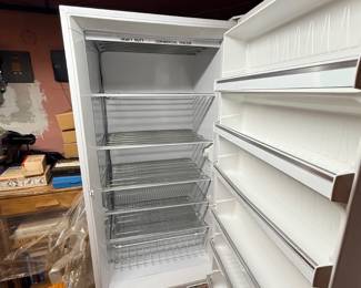 White heavy-duty commercial upright freezer shown open with wire racks and door shelving.