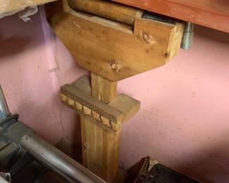 Vintage wooden bench vise attached to a workshop table, showing natural wood grain and light wear from use.