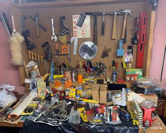 Workshop bench and pegboard filled with assortment of vintage hand tools, including hammers, screwdrivers, wrenches, and clamps.