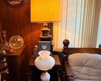 Vintage living room corner featuring a tall table lamp with a textured fabric shade, a milk glass Hurricane-style lamp, and dark wood furniture.