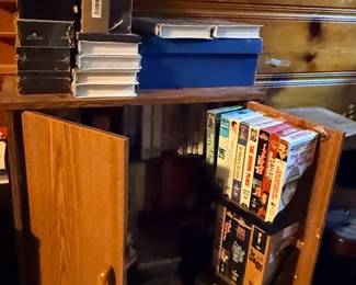 Vintage oak-finish media storage cabinet filled with assorted VHS tapes, DVDs, and boxed media sets.