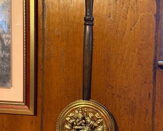 Vintage decorative brass bed warmer with a turned dark wood handle, featuring an embossed pub scene on the lid.