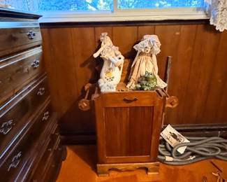Vintage wooden dry sink cabinet displayed with a floral pitcher, a porcelain doll in bonnet, and a ceramic frog figurines next to a tall wooden dresser.